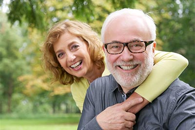 man smiling with his wife after getting dental implants at Pinewood Family Dental